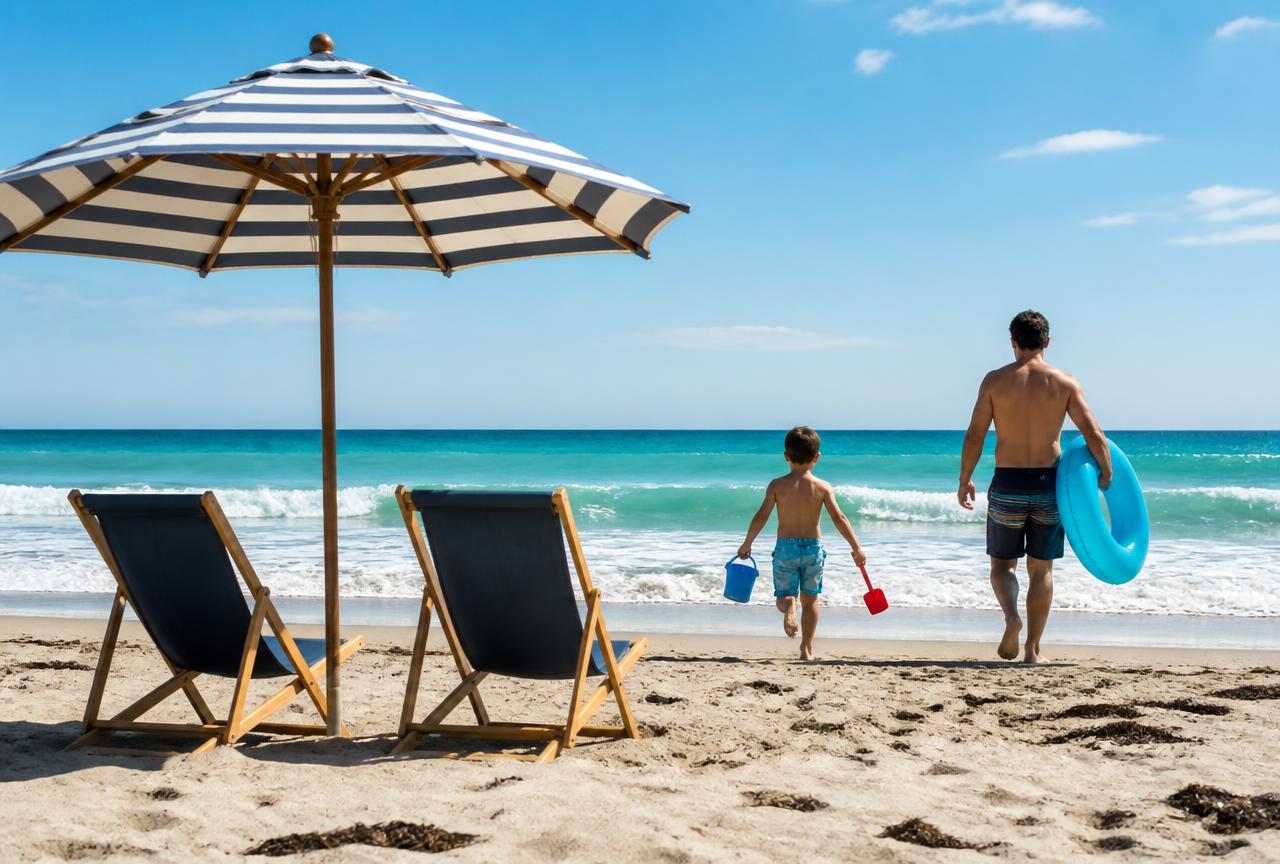 Two beach chairs and a striped umbrella facing the ocean while a child with a bucket and shovel and an adult with a pool float walk toward the water in South Florida.