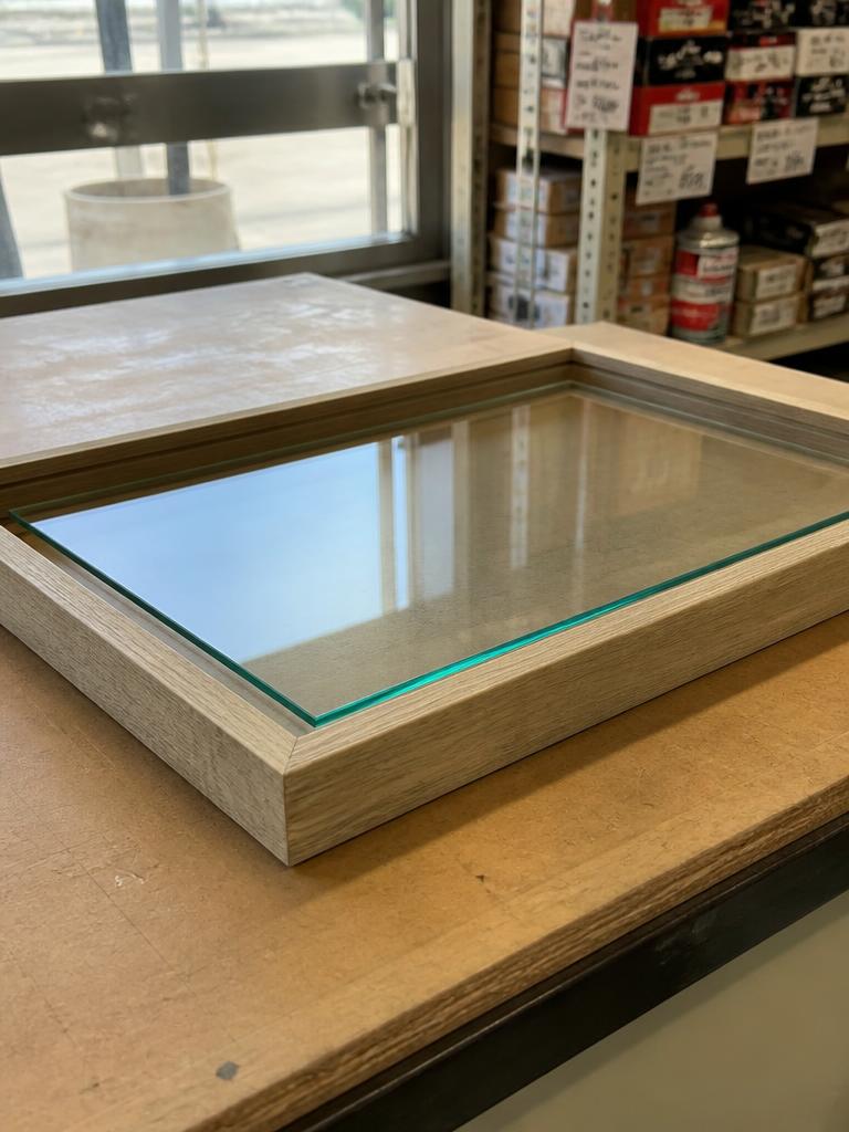 Clear glass cut to size for a wooden picture frame on a workbench