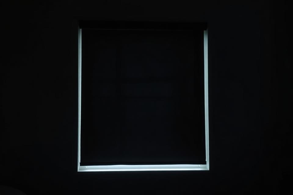 Daylight halo around the edges of an inside-mounted blackout shade in a dark bedroom