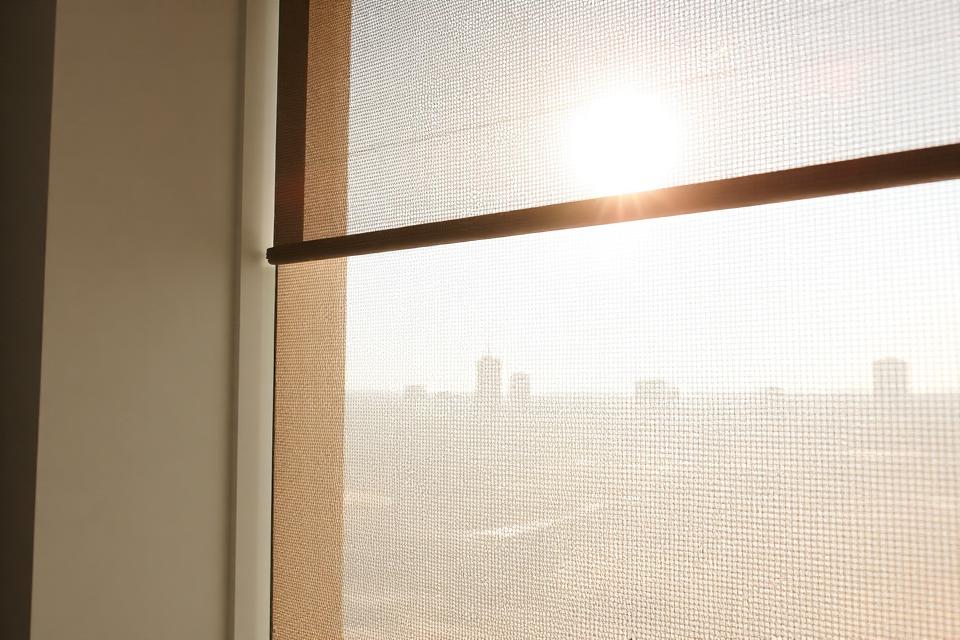 Sunlight through a solar screen shade showing the weave openings