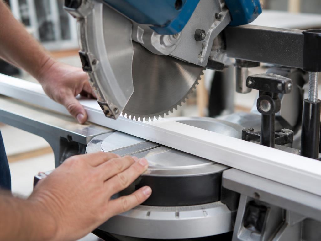 White screen frame stock being cut to length at a 90 degree angle on a saw